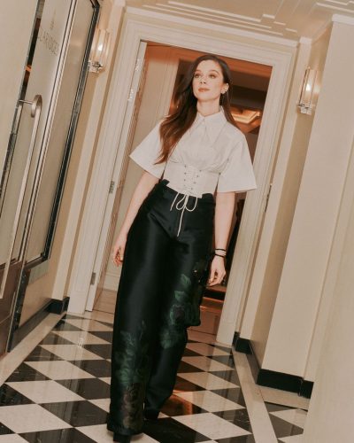 Claudia Jessie in elegant lace-up gray top and black trousers.