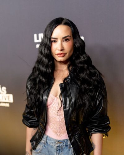 Demi Lovato high-waisted denim shorts, black leather jacket, lace bodysuit.