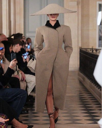 Deva Cassel beige coat with bold statement oversized hat