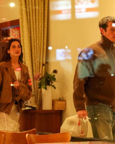 Dua Lipa in a white gown with intricate feather accents.