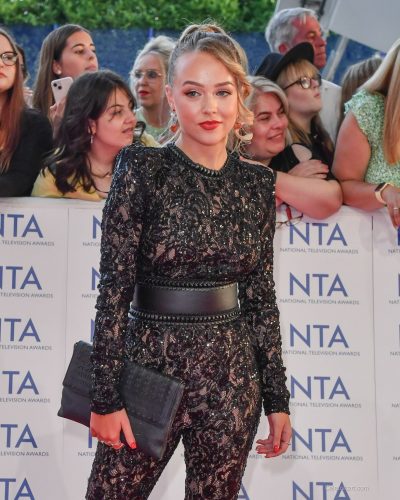 Ellie Dadd in black lace jumpsuit with striking lip color.