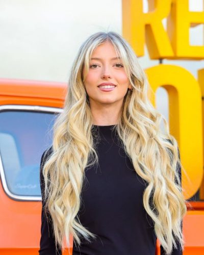 Emily Dobson chic black dress against vibrant orange backdrop