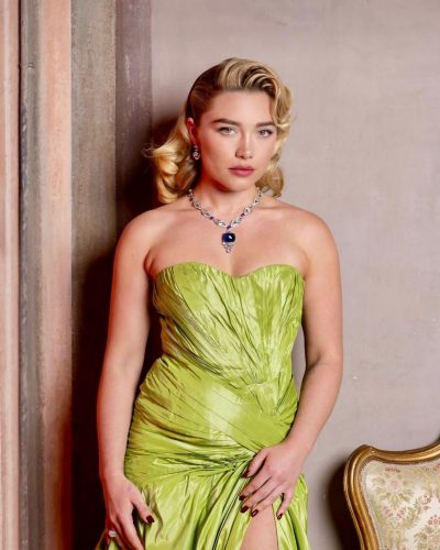 Florence Pugh wearing a green satin gown with a deep blue necklace.