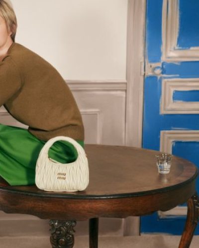 Gigi Hadid with dark skirt and bold orange handbag.