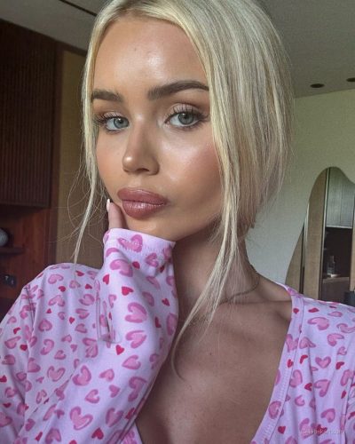 Julia Cavanagh seated in a pink bodysuit, relaxed vibe.