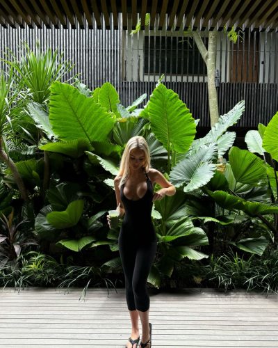 Julia Cavanagh in a stylish black outfit surrounded by greenery.