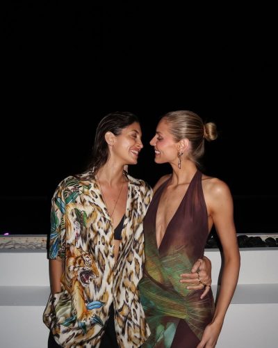 Kari Riley in a vibrant bikini against golden sands and blue seas.