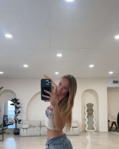 Kyla Dodds in a white crop top paired with denim shorts.