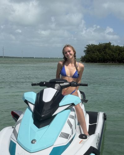 Kyla Dodds in blue bikini smiling by the water.