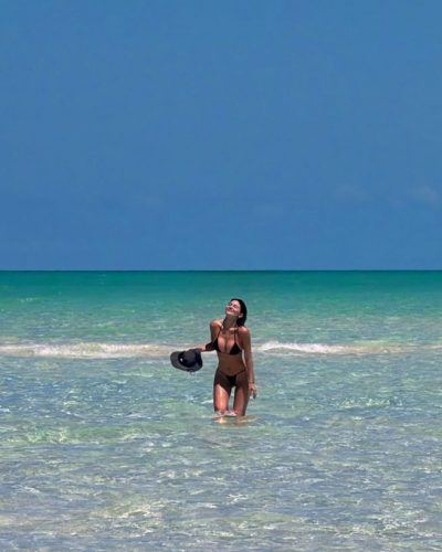Kylie Jenner in black bikini enjoying sunny beach day.