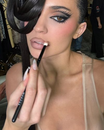 Kylie Jenner in eye-catching yellow coat with dark background