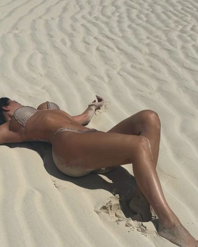 Kylie Jenner in fashionable beige bikini near the waves.