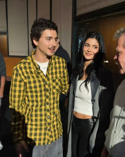 Kylie Jenner wearing sleek black pants with grey long coat.