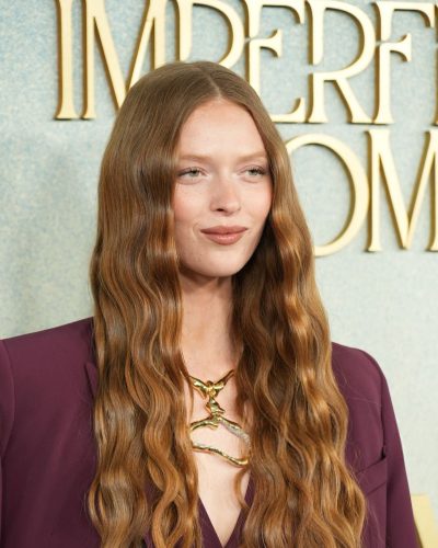 Larsen Thompson in maroon suit with flowing hair and necklace