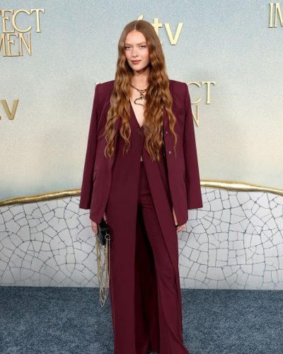 Larsen Thompson in deep maroon suit complemented by black handbag