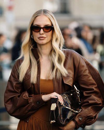 Leonie Hanne wearing a brown leather jacket and pleated dress.