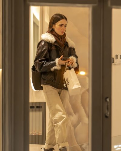 Lily Collins wearing cozy brown turtleneck under leather jacket