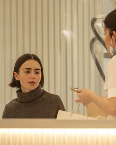 Lily Collins in dark brown leather jacket with white trimming