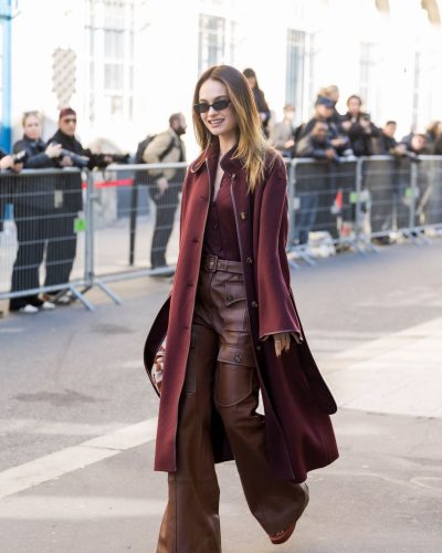 Lily James wearing maroon coat with chic leather trousers