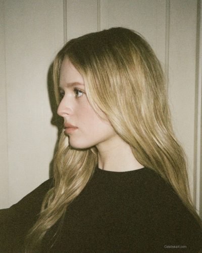 Lulu Wilson in black top, denim shorts, and sheer tights.