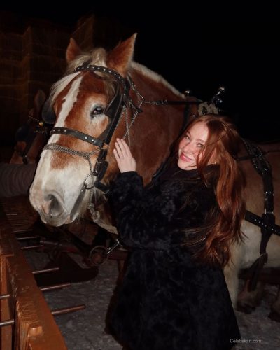 Madeline Ford wearing pink sweater with fluffy winter footwear.