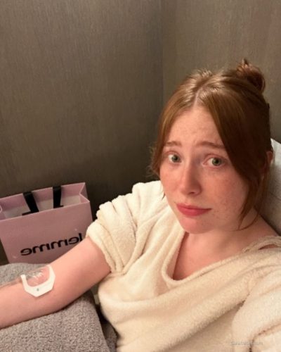 Madeline Ford in pink layered sweater and fashionable boots.