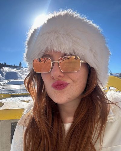 Madeline Ford wearing colorful patterned sweater and fluffy boots.