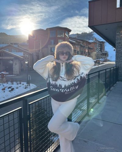 Madeline Ford in light pink knit sweater and fitted outfit.