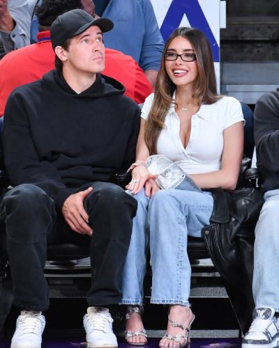 Madison Beer dressed in a white button-up with light blue jeans.