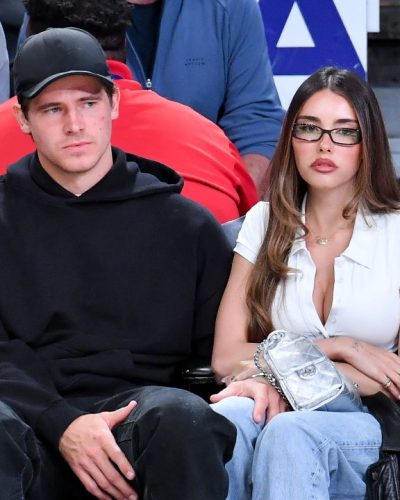 Madison Beer in a fitted white button-up top and light blue jeans.