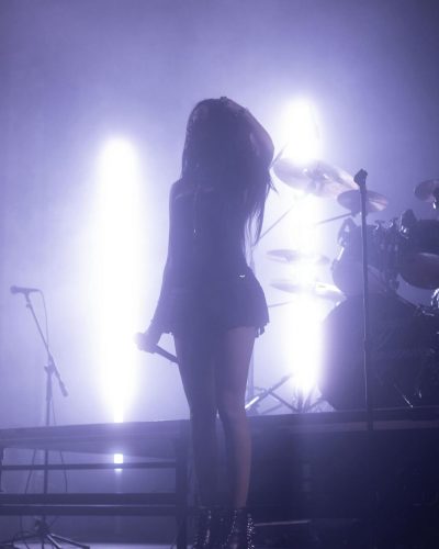 Maggie Lindemann in black fitted dress with spike-heeled boots.