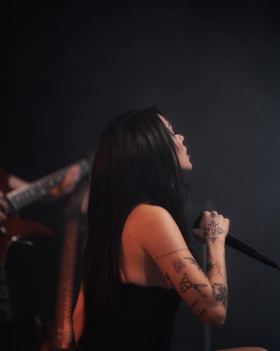 Maggie Lindemann in a black dress styled with long straight hair.