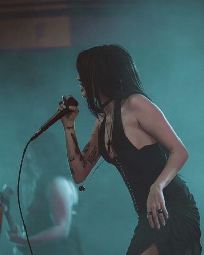 Maggie Lindemann in a black dress a side slit detail.