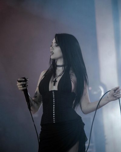 Maggie Lindemann in a sleek black dress with layered necklaces.