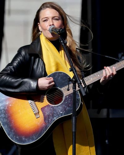 Maggie Rogers casual black leather jacket and yellow scarf