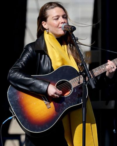 Maggie Rogers black leather jacket and bright yellow scarf