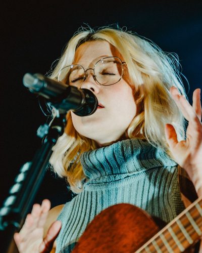 Maisie Peters in a ribbed dress with knee-high black footwear.