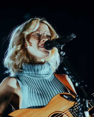Maisie Peters wearing a stylish ribbed dress with high-neck design.