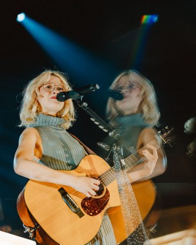 Maisie Peters wearing a high-neck mini dress in soft pastel shade.