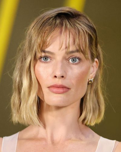 Margot Robbie chic statement bag with unique jewelry.