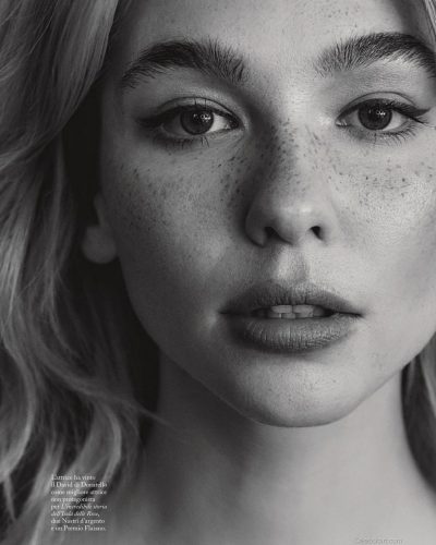 Matilda De Angelis in red pleated dress with off-the-shoulder cut