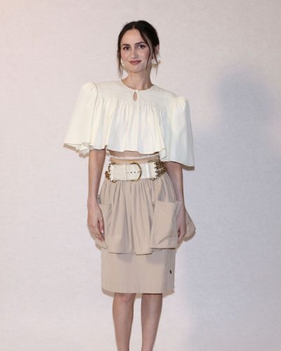 Maude Apatow chic statement belt with white top and beige skirt