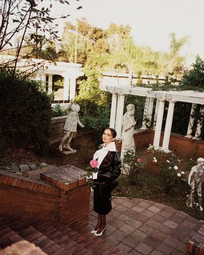 Maude Apatow in a black gown with a stylish flower necklace.