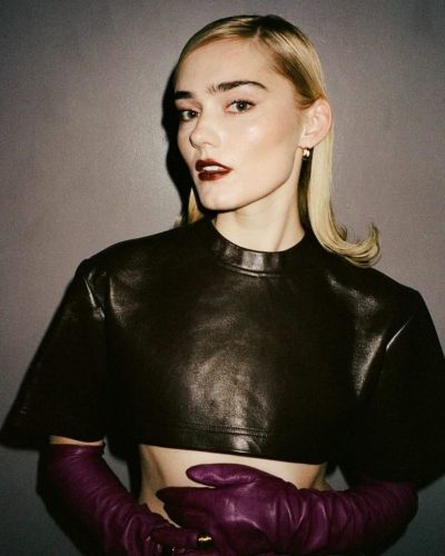 Meg Donnelly modern leather top, soft beige trousers, attention-grabbing purple gloves