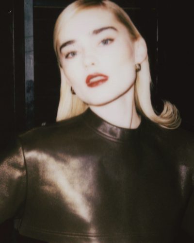 Meg Donnelly fashionable leather top, relaxed beige trousers, colorful purple gloves