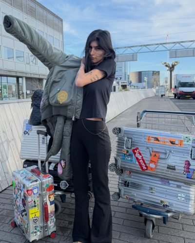 Mia Khalifa dressed in black flared pants and relaxed top.