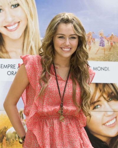 Miley Cyrus wearing ruffled pink top with casual blue jeans