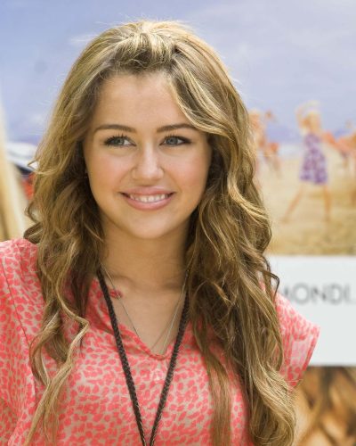 Miley Cyrus in bright pink top with fashionable blue jeans