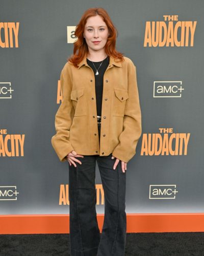 Mina Sundwall with vibrant red hair in brown jacket and black pants.