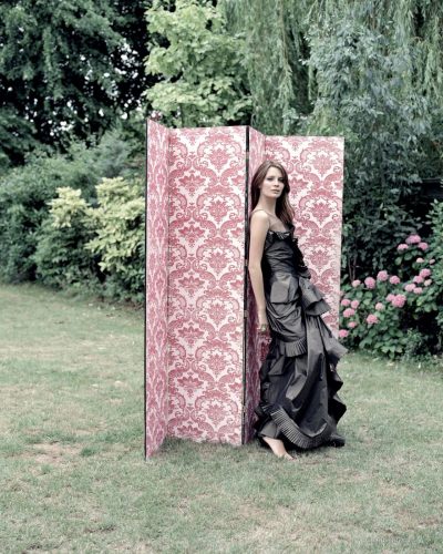 Mischa Barton in a relaxed red dress surrounded by greenery